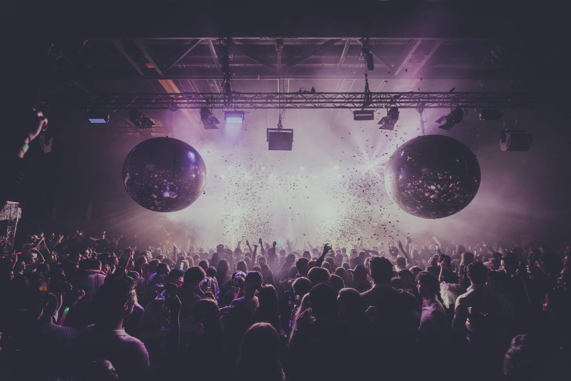 Festival crowd under mirror balls, confetti and stage lights
